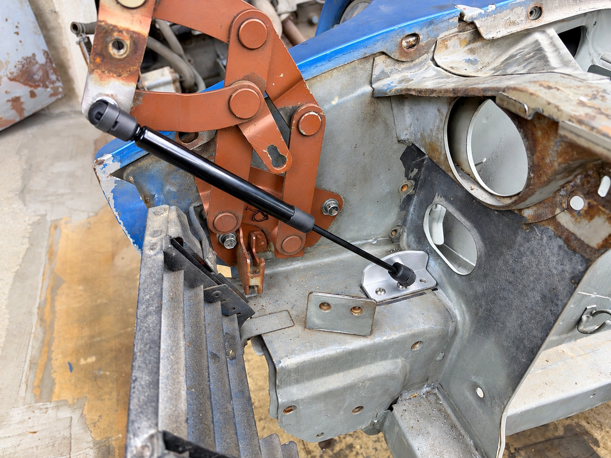 Skillard hood strut installed on a Datsun 280Z, showing the hood hinge attachment and lower mounting bracket.
