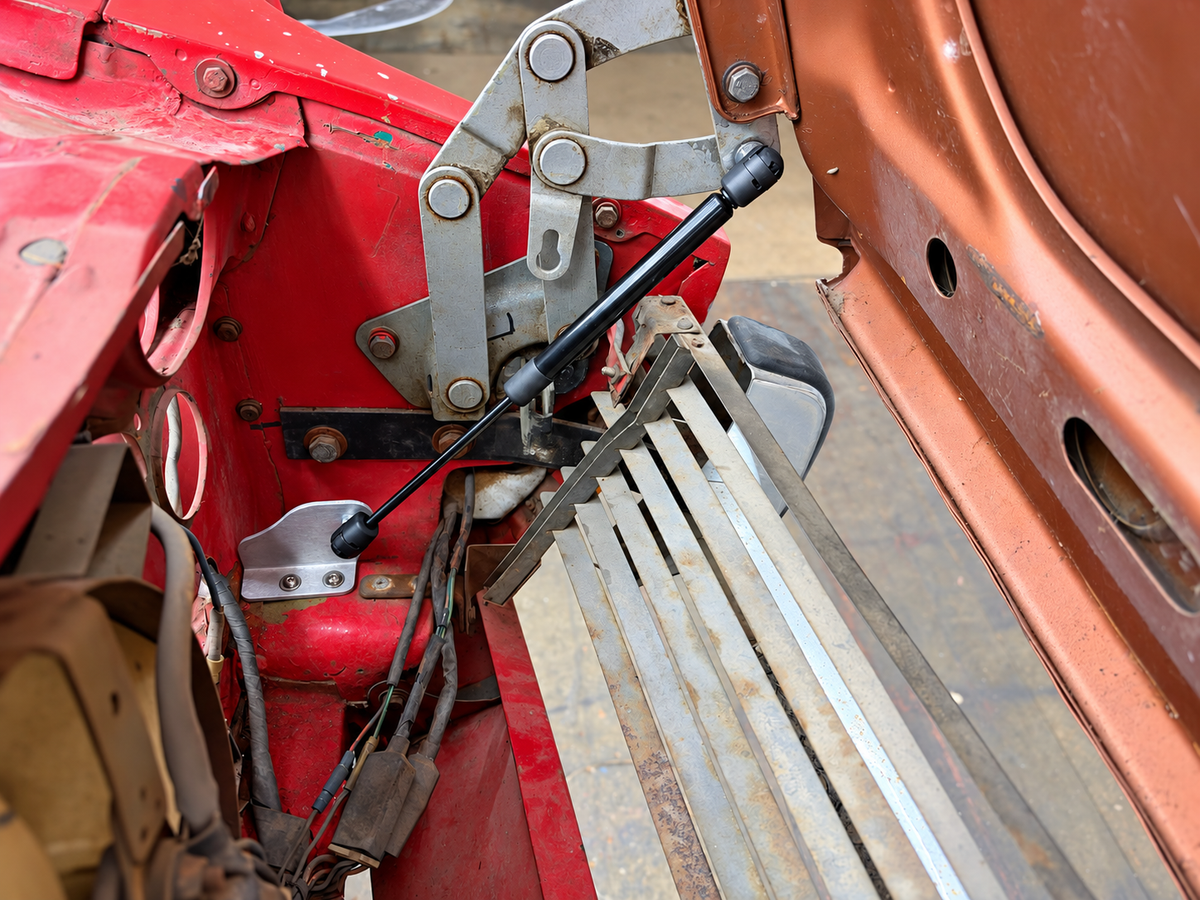 Skillard hood strut installed on a Datsun 240Z, showing the hood hinge attachment and lower mounting bracket.